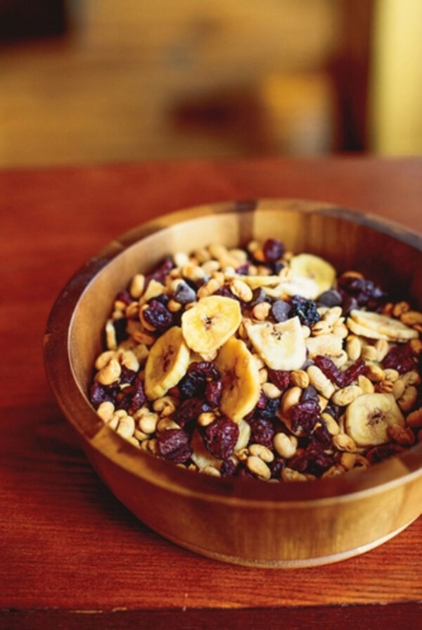 A wooden bowl filled with Tosteds Trail Mix.