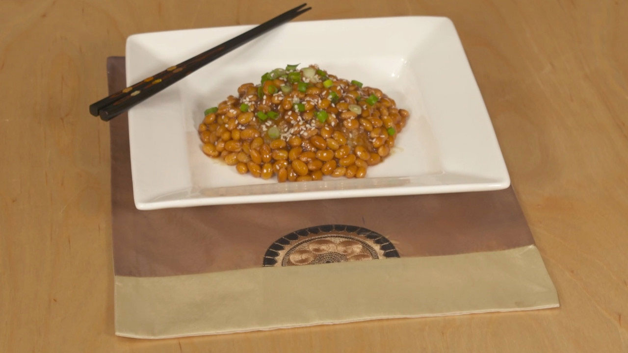 A rectangular white plate with korean soybeans and two chopsticks.