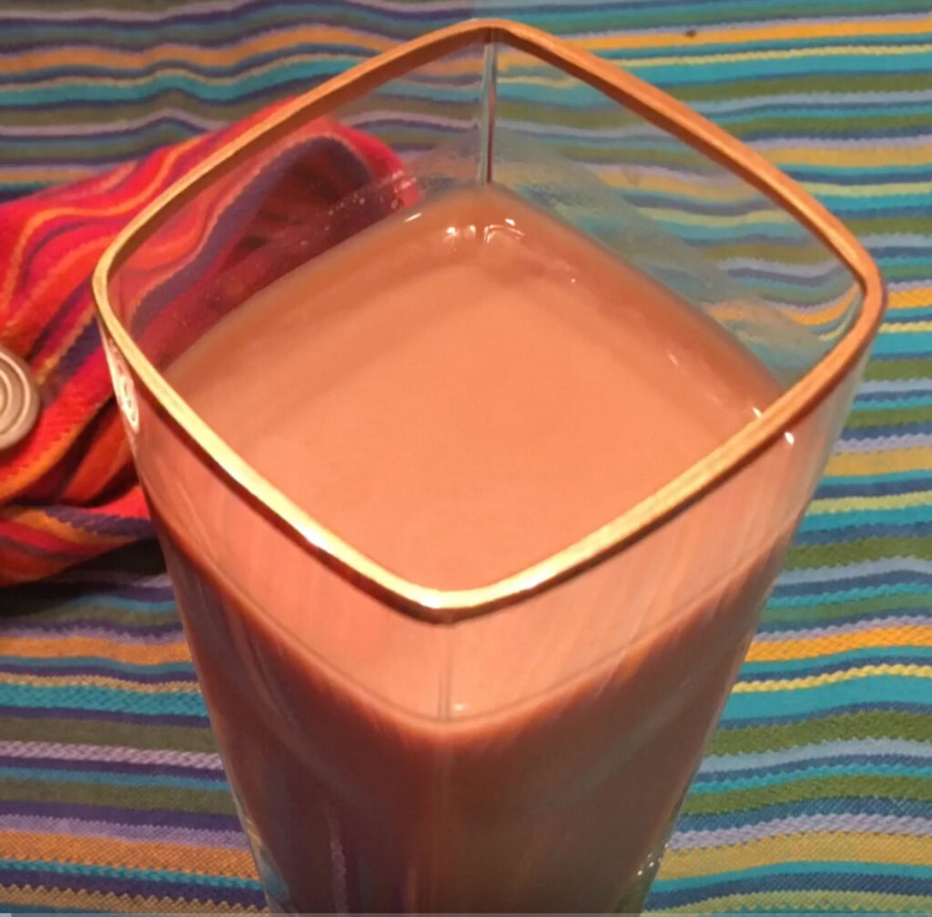 A glass filled with a pink-red colored smoothie.