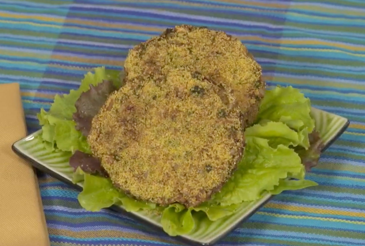 A square plate with Okara burgers on top of a bed of lettuce.