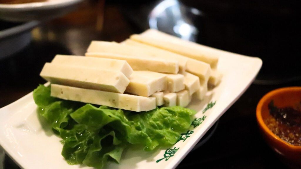 Long, rectangular sticks of tofu arranged on a rectangular white plate.